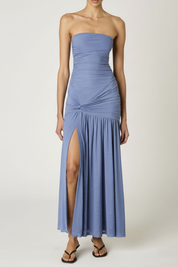 Woman wearing a strapless blue gown with a slit on a white background